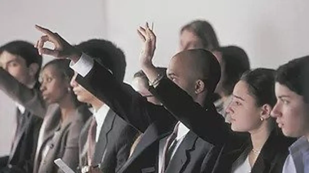 Image of several people raising their hands.